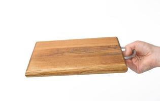 female hands hold empty rectangular brown wooden chopping board on white background photo