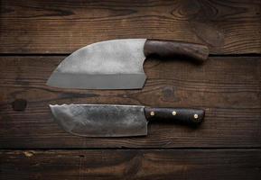 metal sharp kitchen knives in a wooden handle on a brown table made of boards, top view photo