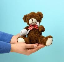 funny vintage brown curly teddy bear with rewound paw with white gauze bandage on a blue background photo