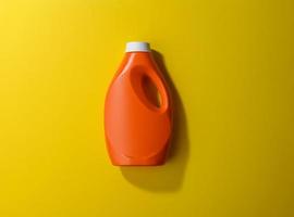 botella de plástico naranja para detergente en polvo líquido sobre fondo amarillo foto