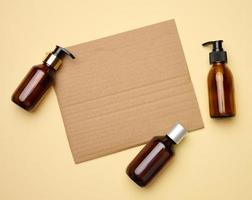 blank brown sheet of corrugated paper and brown glass bottles with dispenser beige background. Packaging for gel, serum, advertising and promotion. Natural organic products. photo