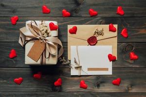 Gift box and greeting card with bow ribbon and paper hearts on wooden table for Valentines day. copy space. photo