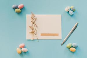 huevos de Pascua sobre fondo azul y tarjeta de felicitación con espacio para copiar texto foto