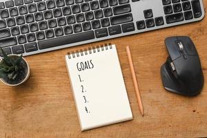 Business concept New year Goals, keyboard on wood table with note photo