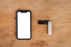 Mobile phone and Hardware wallet on wooden table background photo