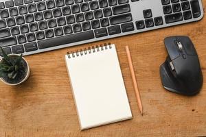 Wood desk table with blank notebook with pencil, keyboard computer and supplies photo