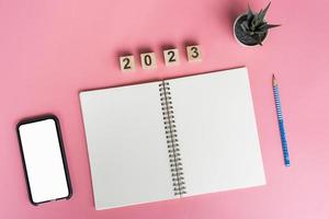 cuadernos con objetivos vacíos para el año 2023 y teléfono con fondo de color foto