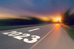 Motion blur empty asphalt road and New year 2023 concept. Driving on an empty road to Goals 2023 with sunset. photo