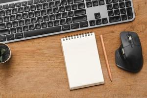 Wood desk table with blank notebook with pencil, keyboard computer and supplies photo