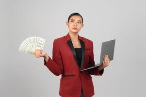 Young beautiful woman in formal clothing for officer hold banknote and laptop photo