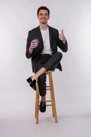 Portrait of happy smiling young businessman showing thumbs up gesture and holding coffee on isolated over white background photo