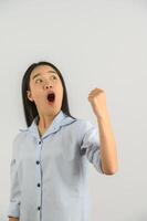 Portrait of young asian woman showing winner gesture over isolated white background photo