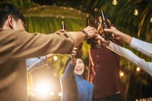 Portrait of Happy Asian friends having dinner party together - Young people toasting beer glasses dinner outdoor  - People, food, drink lifestyle, new year celebration concept. photo