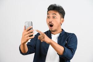 Protrait of Young asian man expressing surprise while using mobile phone isolated over white background photo