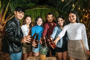 Portrait of Happy Asian friends having dinner party together - Young people toasting beer glasses dinner outdoor  - People, food, drink lifestyle, new year celebration concept. photo