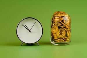 Saving gold coins in glass jars on green background, coin savings concept photo