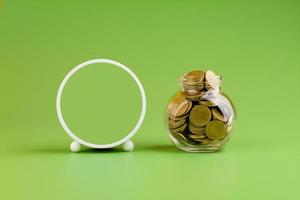 Saving gold coins in glass jars on green background, coin savings concept photo