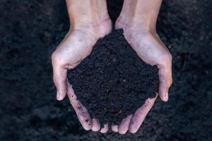 manos sosteniendo abundante suelo para la agricultura o preparándose para plantar el concepto de melocotón. probando muestras de suelo en las manos con fondo de suelo. concepto de calidad del suelo y agricultura. jardinería. foto