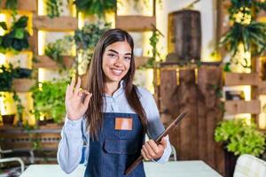bella camarera sonriendo en el restaurante sosteniendo un menú y mostrando el cartel de ok. foto