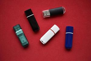 Colored flash drives on a red background. Storage of information. Flash drives in a pile. photo