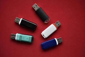 Colored flash drives on a red background. Storage of information. Flash drives in a pile. photo