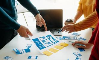 Close up view of UI developer team brainstorming on their project with laptop, smartphone and digital tablet. Creative digital development agency. photo
