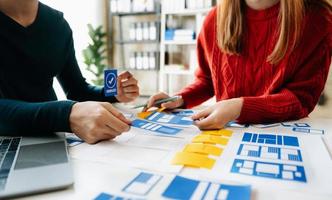 UX developer and ui designer brainstorming about mobile app interface wireframe design with customer breif and color code at office. photo