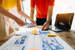 UX developer and ui designer brainstorming about mobile app interface wireframe design with customer breif and color code at modern office. photo