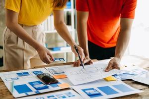 UX developer and ui designer brainstorming about mobile app interface wireframe design with customer breif and color code at modern office. photo