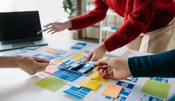 El equipo de desarrolladores de ui hace una lluvia de ideas sobre su proyecto con una computadora portátil, un teléfono inteligente y una tableta digital. agencia creativa de desarrollo digital. foto