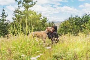 Beautiful woman kissing her greyhound dog outdoors. photo