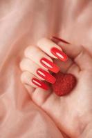 manos de niña con manicura roja y corazón decoratine foto