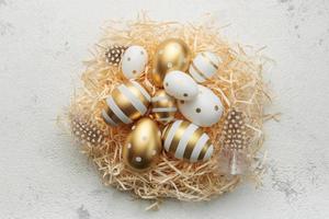 Easter eggs painted with gold paint on a straw background photo