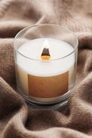 A candle burns on the background of a knitted sweater. photo