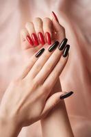 Hands of a young girl with red  and black manicure on nails photo