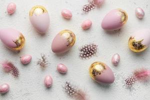 Easter eggs are painted with violet and gold paint on a gray concrete background.