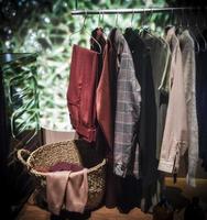 A row of multicolored clothes hanging next to a laundry basket photo