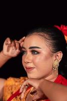 a Sharp gaze from an Indonesian woman with makeup on her face while wearing an orange dress and golden earrings photo