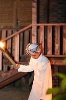 An Islamic man wearing a Muslim dress in the dark night with the fire torch lighting photo