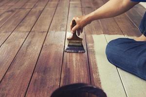 pintar a mano el color del aceite en el piso de madera, concepto de trabajo en casa diy foto