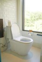 white toilet in restroom with window photo