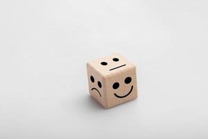 Mental health and emotional state concept, Smile face in bright side and sad face in dark side on wooden block white background photo