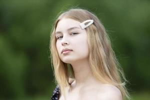 retrato de una hermosa chica con el pelo largo en un fondo de verano. el rostro de una adolescente rubia. foto
