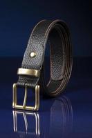 Black leather belt on a dark blue background. photo