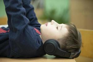 The boy in the headphones lies and listens to music. photo