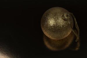 bola de navidad dorada sobre un fondo negro. foto