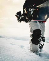 Snowboarder dressed in a full protective gear for extreme freeride snowboarding posing with a snowboard walking. Isolated on gray white snow background. photo