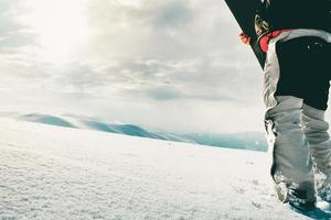 Snowboarder dressed in a full protective gear for extreme freeride snowboarding posing with a snowboard walking. Isolated on gray white snow background. photo