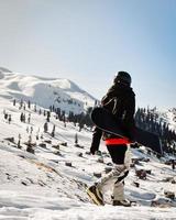 snowboarder vestido con un equipo de protección completo para el snowboard freeride extremo posando con una caminata de snowboard. aislado sobre fondo de nieve blanca gris. foto