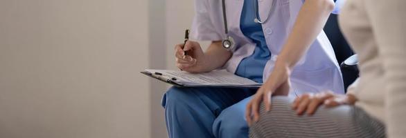 Asian female patient undergoing health check up while female doctor uses stethoscope to check heart rate in nurse, health care concept photo